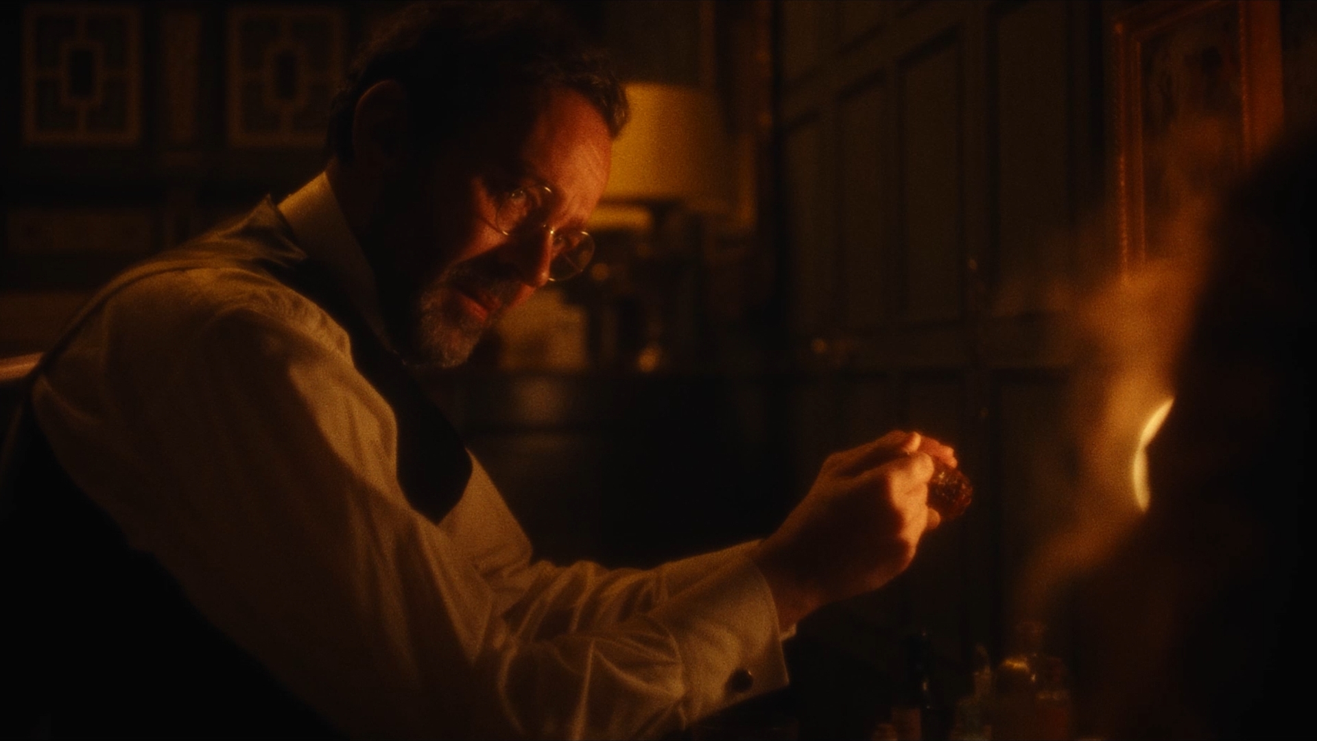 A Victorian doctor holds up a vial of medicine next to a lamp for his patient